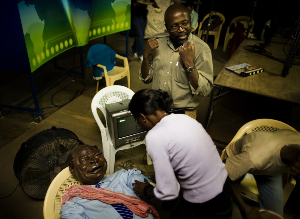 Film crew member adjusting a Kibaki puppet during production at The XYZ Show studio in Nairobi.