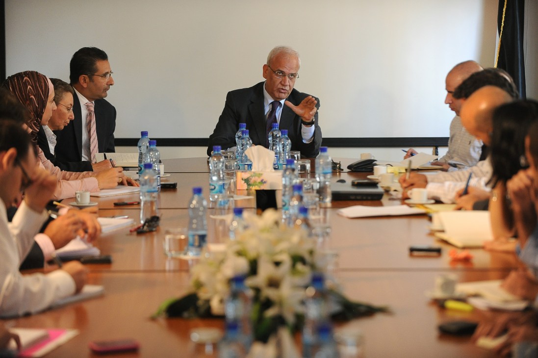 Palestinian negotiator Saeb Erakat gestures while speaking at a conference table surrounded by staff members.