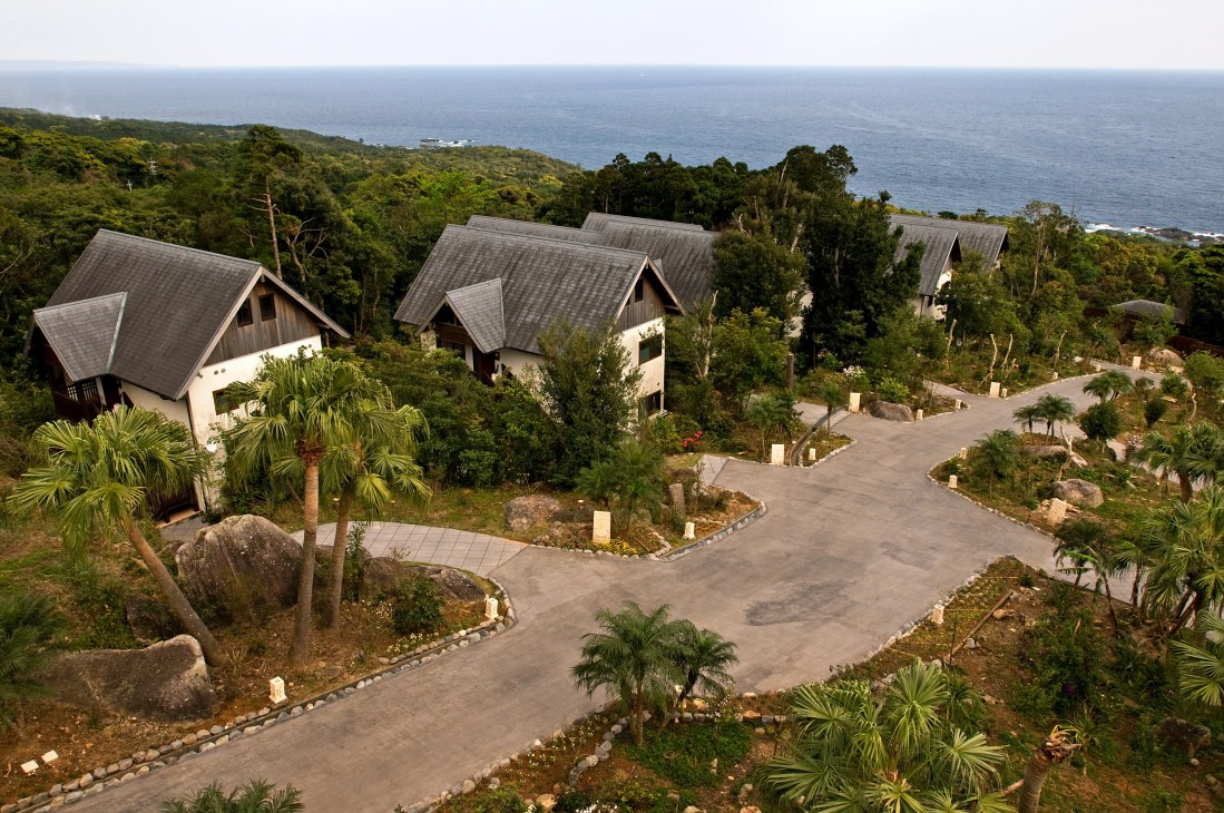 Aerial view of Sankara Hotel villas nestled in forest overlooking the Pacific Ocean.