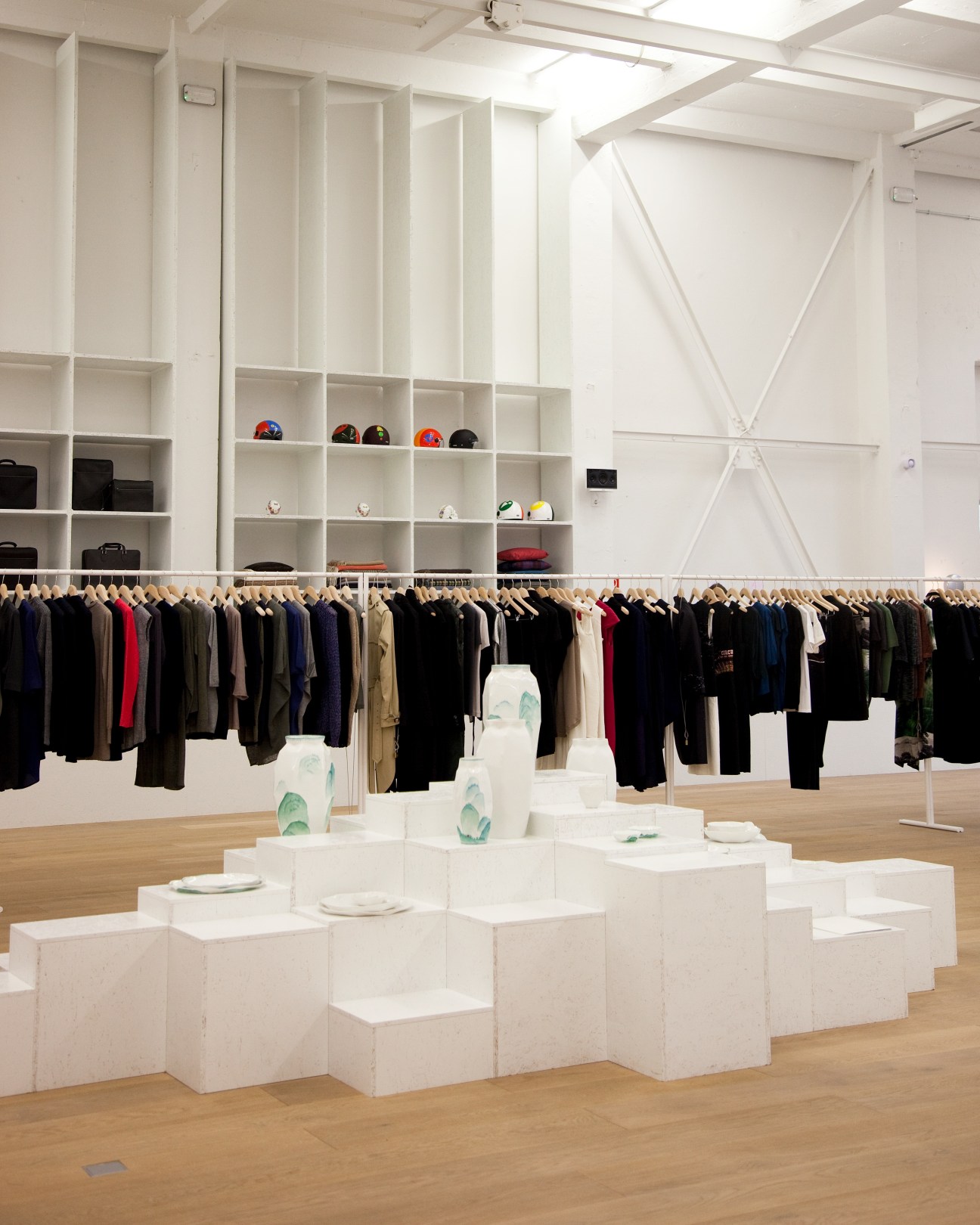 Interior of Andreas Murkudis store in Berlin showing white shelving with clothing racks and display cubes.