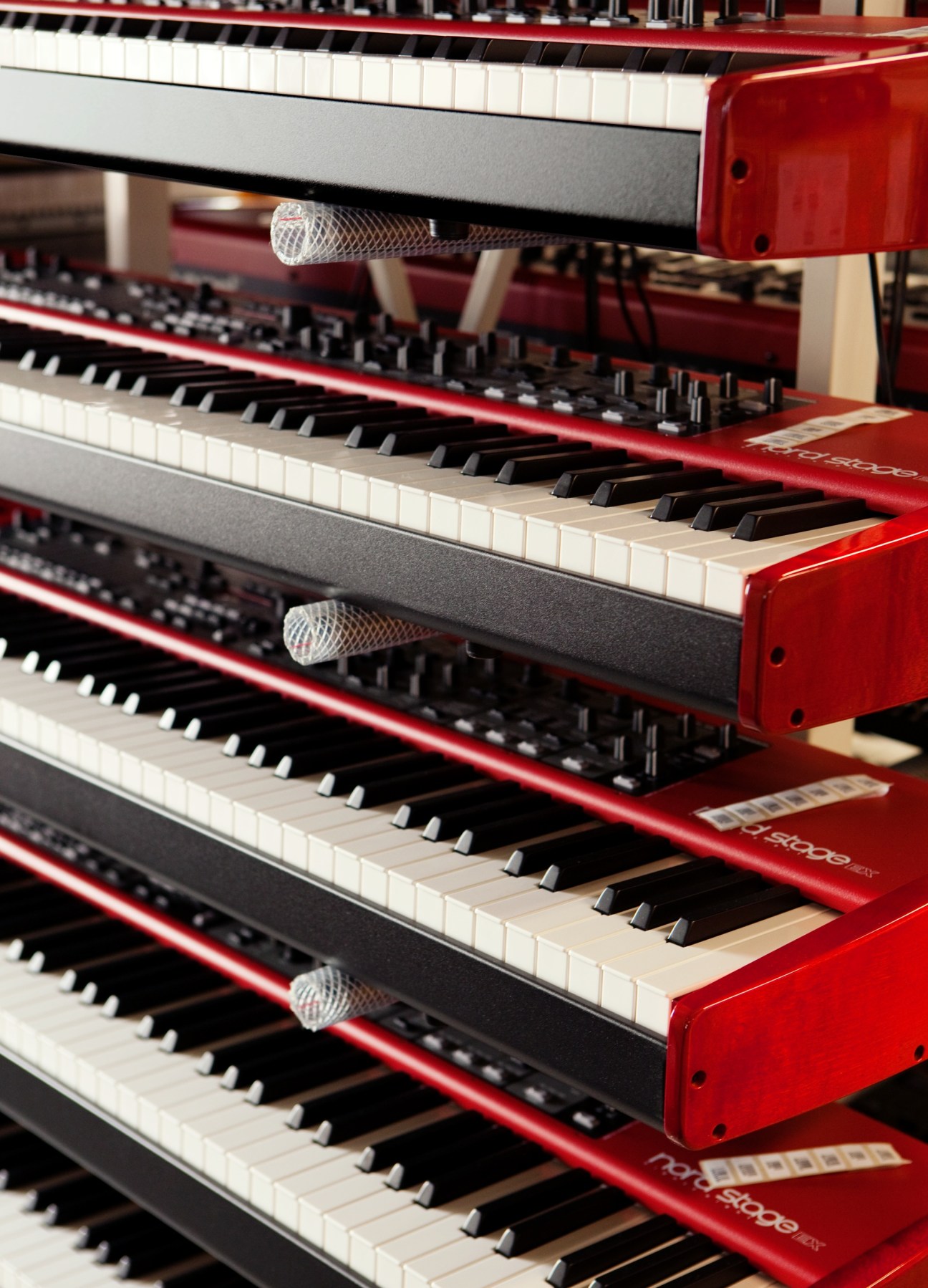 Stacked Nord Stage Ex keyboards with red casings and white keys in Stockholm factory.