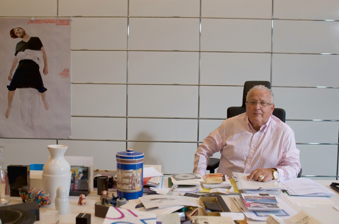 Pierre Keller, ECAL's head, seated at his desk surrounded by design objects and materials.