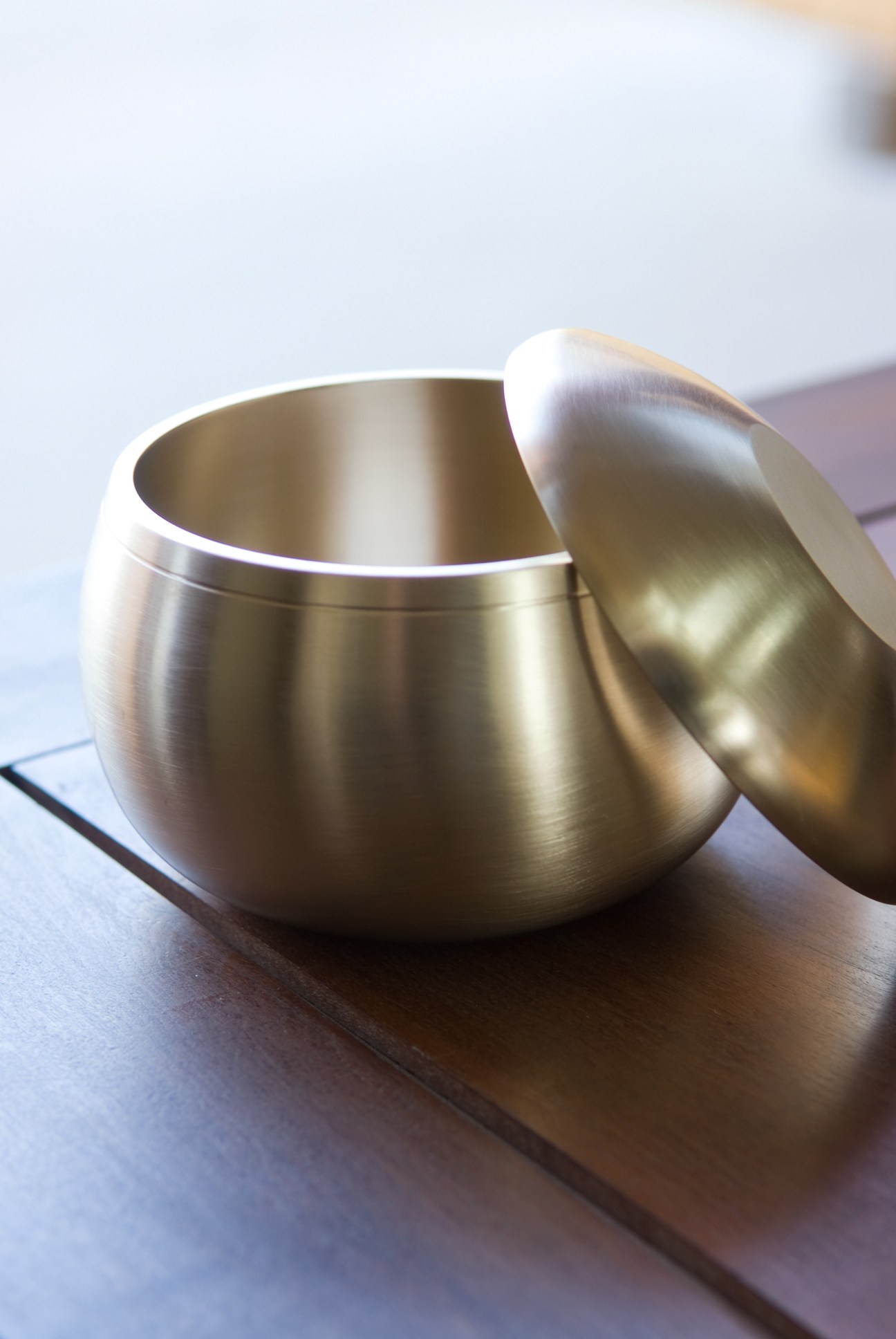 Polished bronze rice bowl with white-gold sheen displayed on wooden surface.
