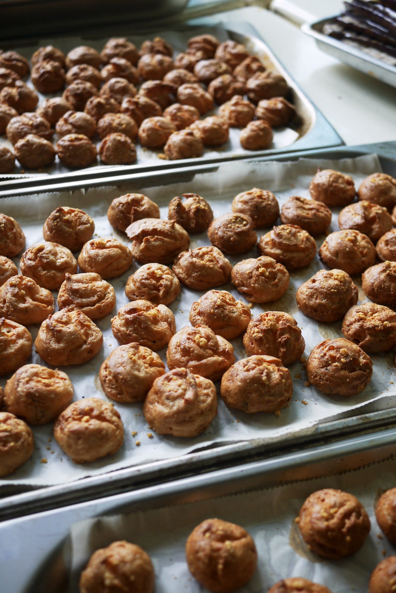 Trays of freshly baked meatballs cooling on parchment paper.