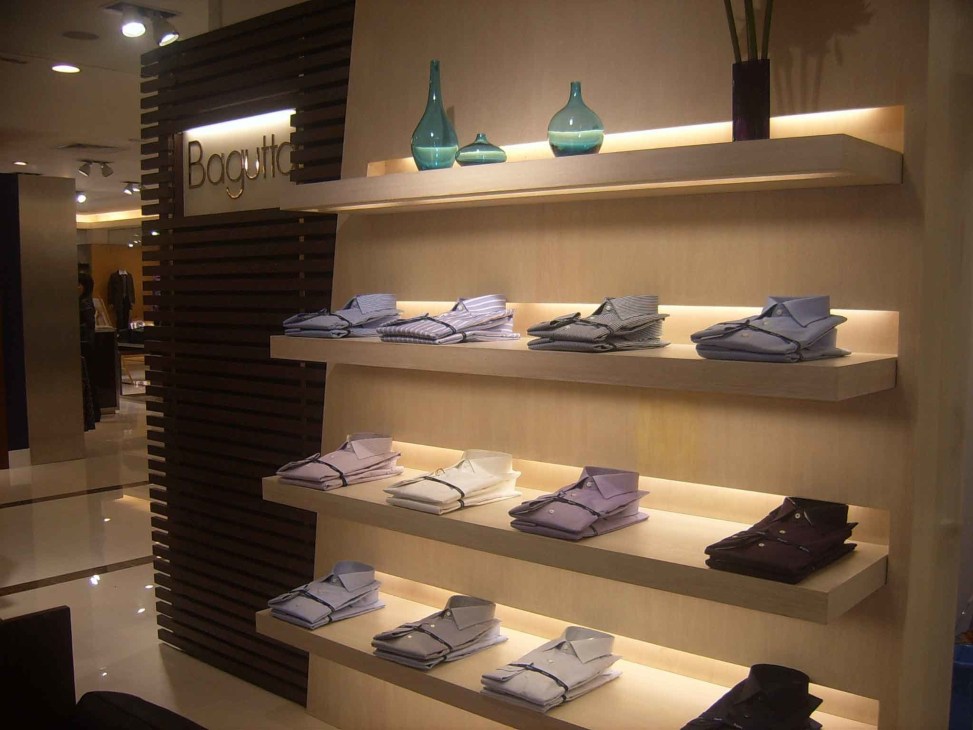 Bagutta retail store interior displaying folded shirts on illuminated shelves with brand signage.