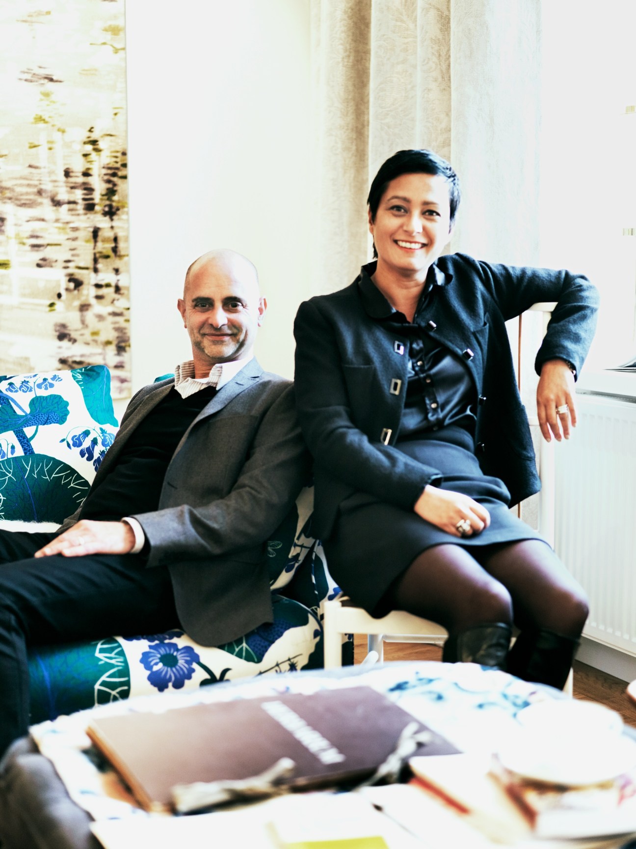 Thommy Bindefeld and Maria Veerasamy sitting on a sofa with patterned blue cushions in the Svenskt Tenn store.
