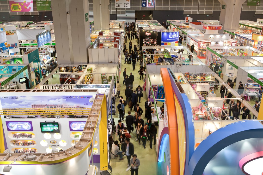 Overhead view of Hong Kong Toys & Games Fair with multiple exhibition booths and visitors walking through aisles.