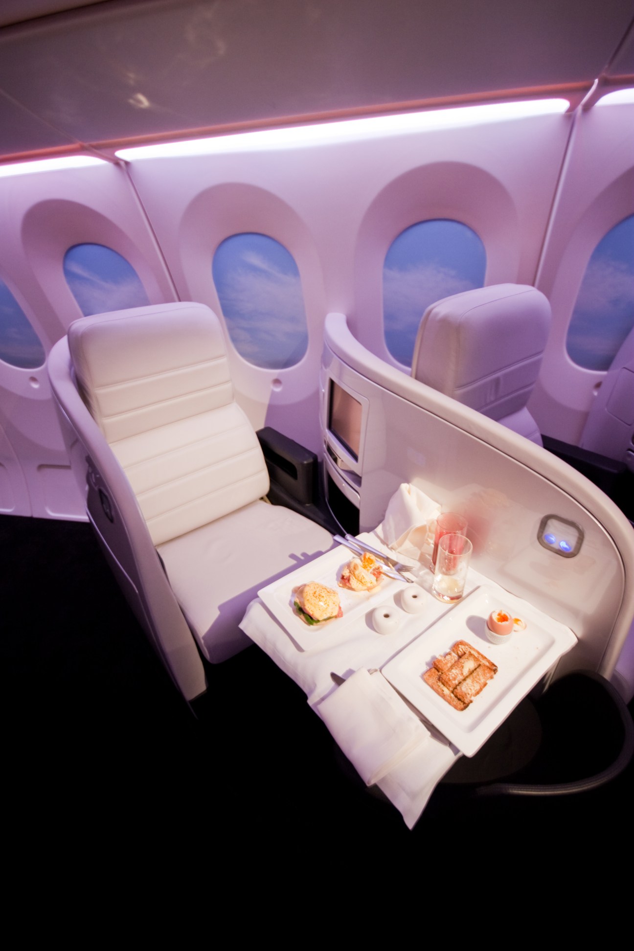 Air New Zealand Business Class lie-flat seat with meal service tray and window views.