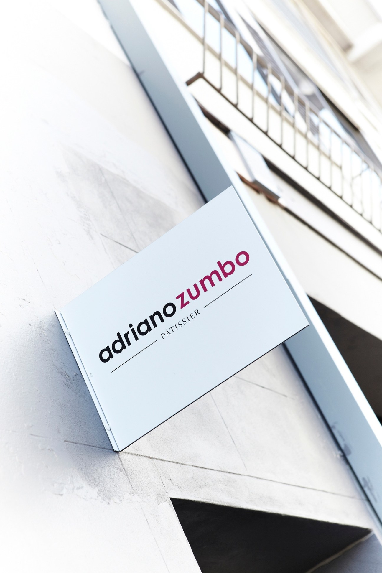 Adriano Zumbo patisserie storefront sign on white building facade in Sydney.