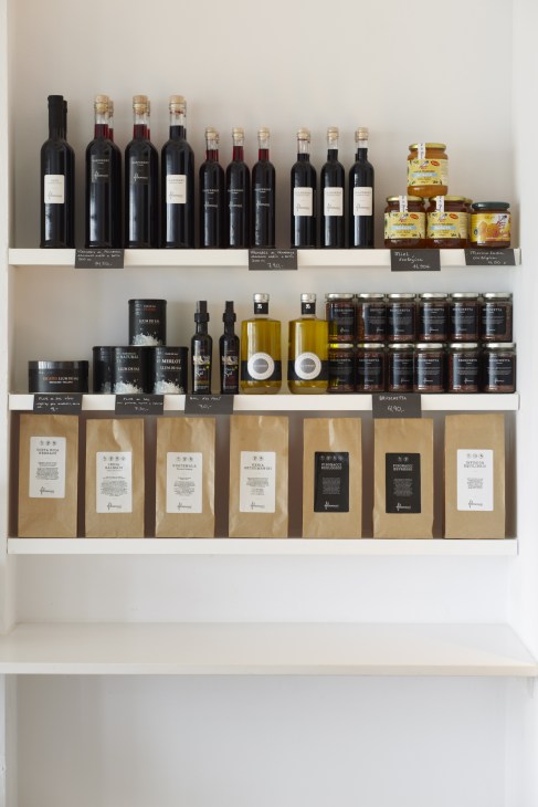 Shelves displaying wine bottles, jars, and kraft paper bags of coffee from Fibonacci bakery in Mallorca.
