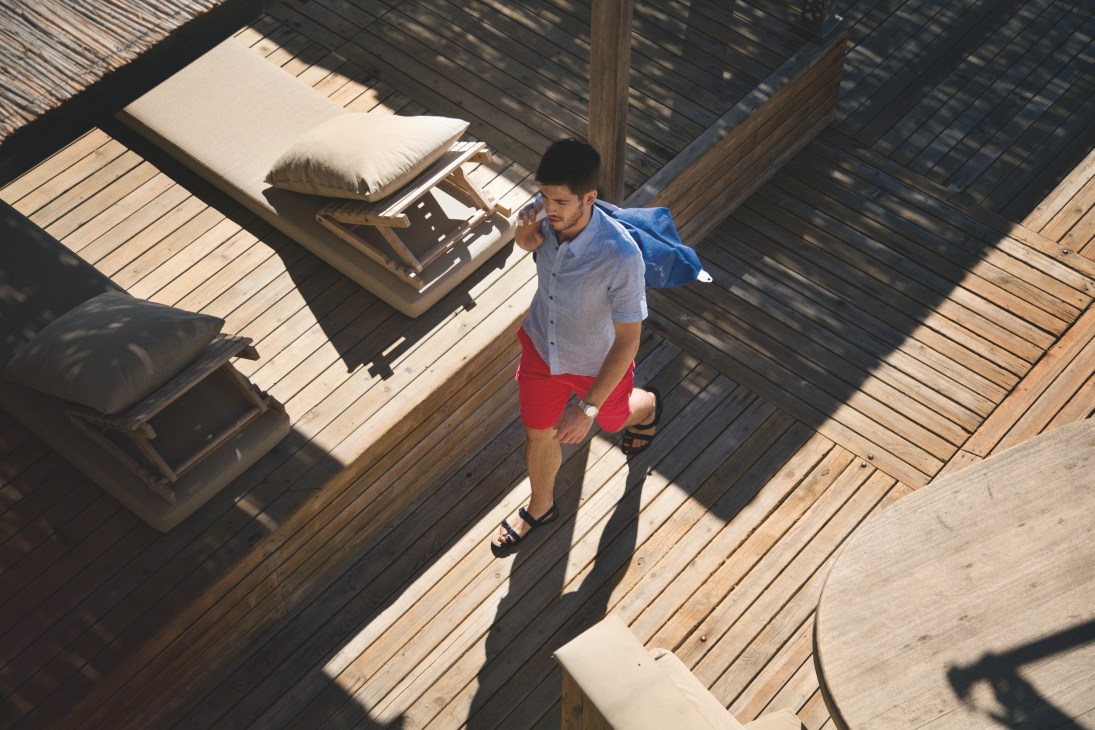 Man wearing Moustache shirt and Post O'alls shorts on wooden deck at Macakizi hotel in Bodrum.