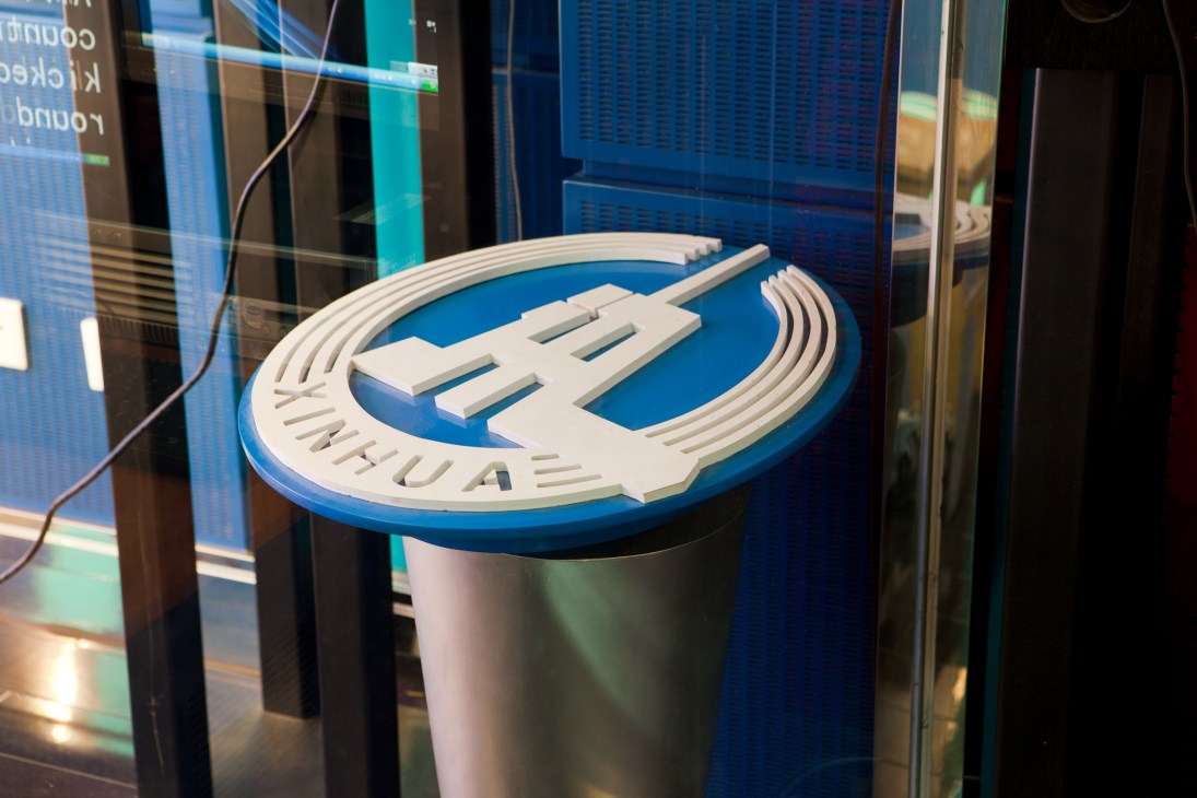 Xinhua logo displayed on a blue circular sign with white lettering in a broadcast facility.
