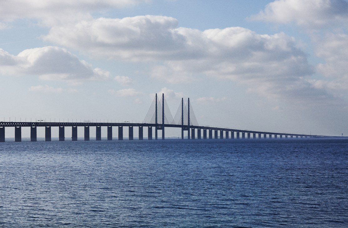 The Øresund Bridge spanning across blue water under a cloudy sky, connecting Sweden and Denmark.