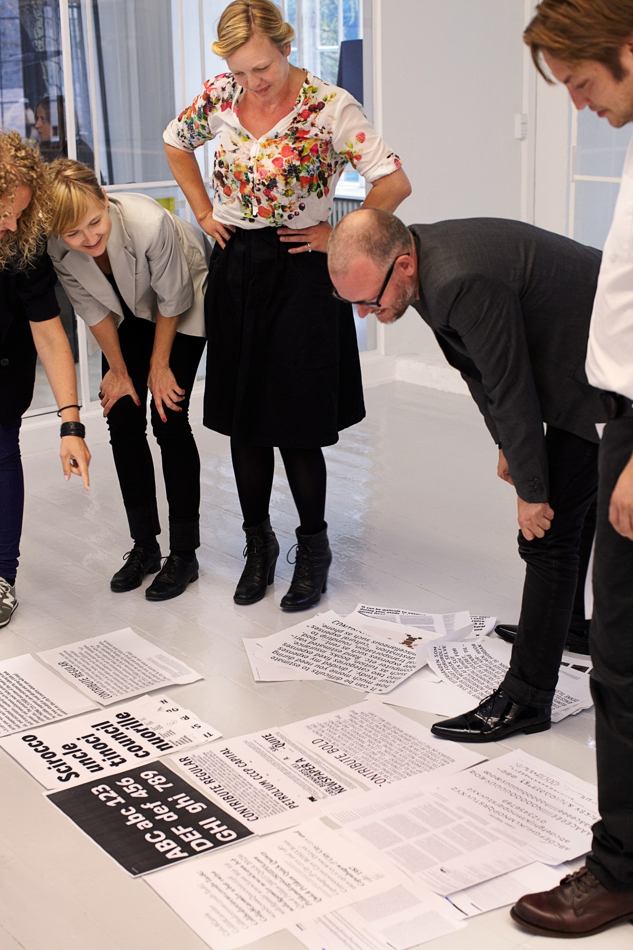 E-Types staff members examining font printouts on a table in their Copenhagen office.