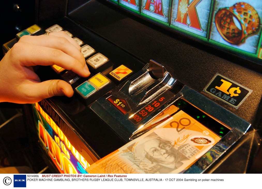 Hand pressing buttons on a poker machine displaying numerical values and game graphics.