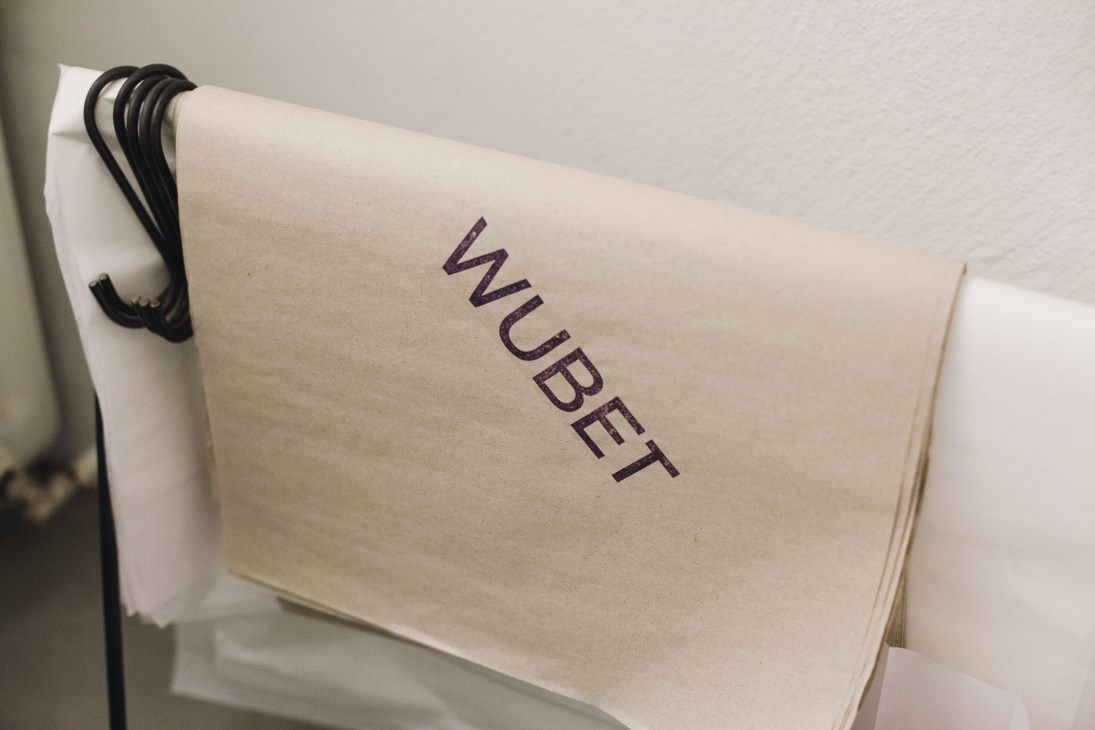 Wubet scarf brand packaging with purple logo text on cream-colored envelope with black cord tie.