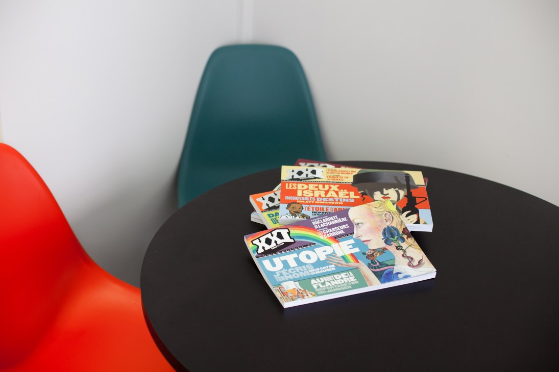 Stack of XXI magazine issues displayed on a black table with colorful covers featuring various illustrated designs and typography.