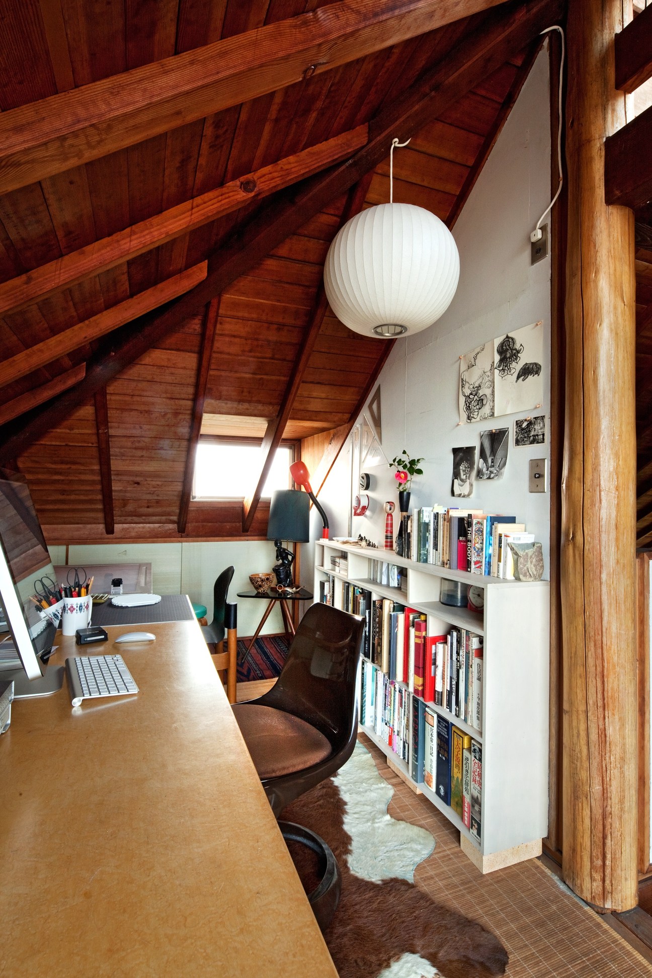 Photographer Shinichi Ito's third-floor studio workspace with wooden beams, desk, computer, bookshelves, and white pendant lamp.