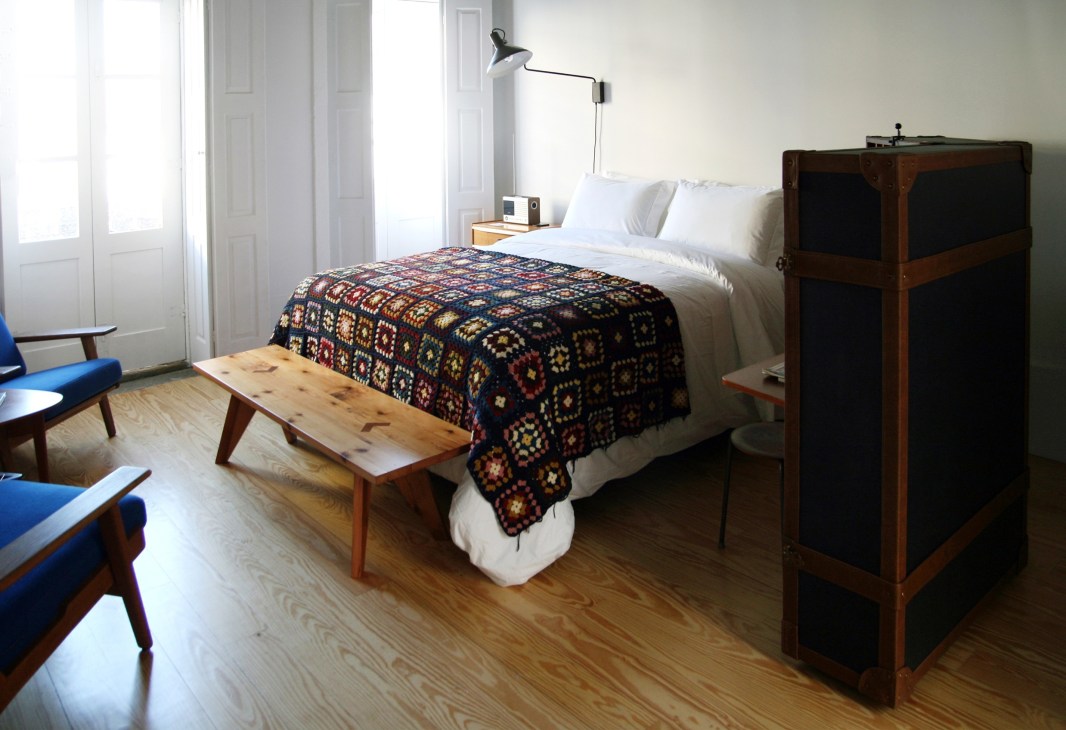 Hotel bedroom at Rosa Et Al in Porto featuring vintage mid-century furniture, patterned bedcover and wooden flooring.