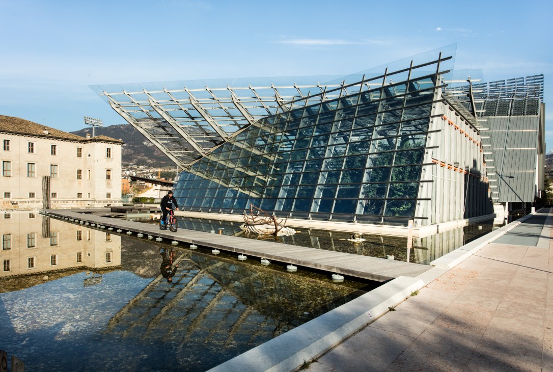 Muse science museum designed by Renzo Piano with a cyclist on a bridge and mountains in background