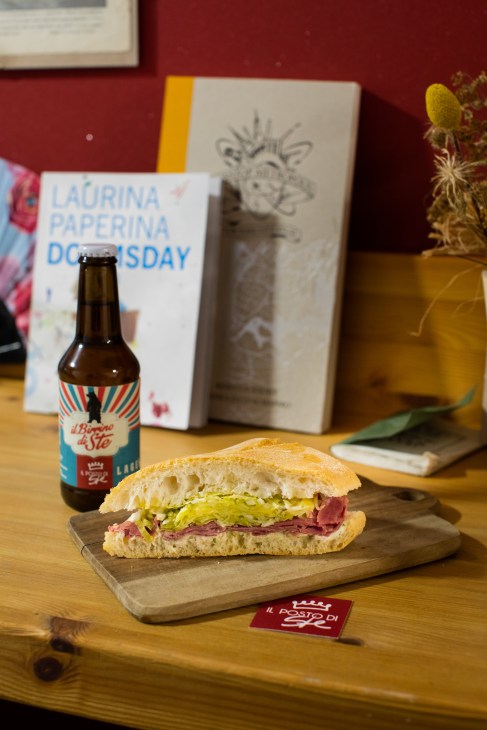Panino Errante sandwich on wooden board with beer bottle and shop interior at Il Posto di Ste.