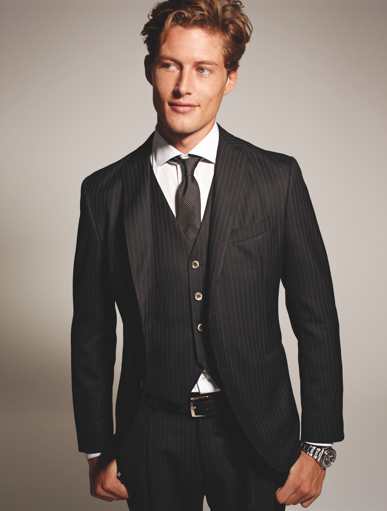 Man wearing a dark pinstriped three-piece suit by Boglioli with white dress shirt, tie, and Seiko watch.