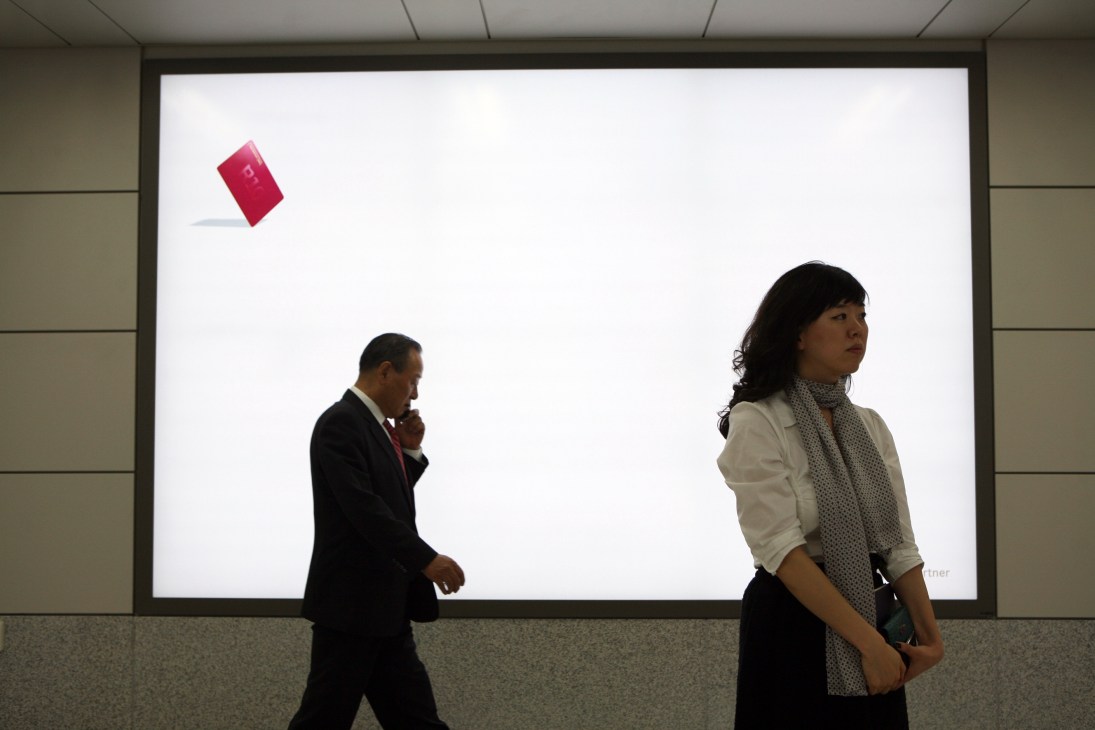 Hyundai Card ad with minimal design showing small red credit card icon on white background with two people passing by.