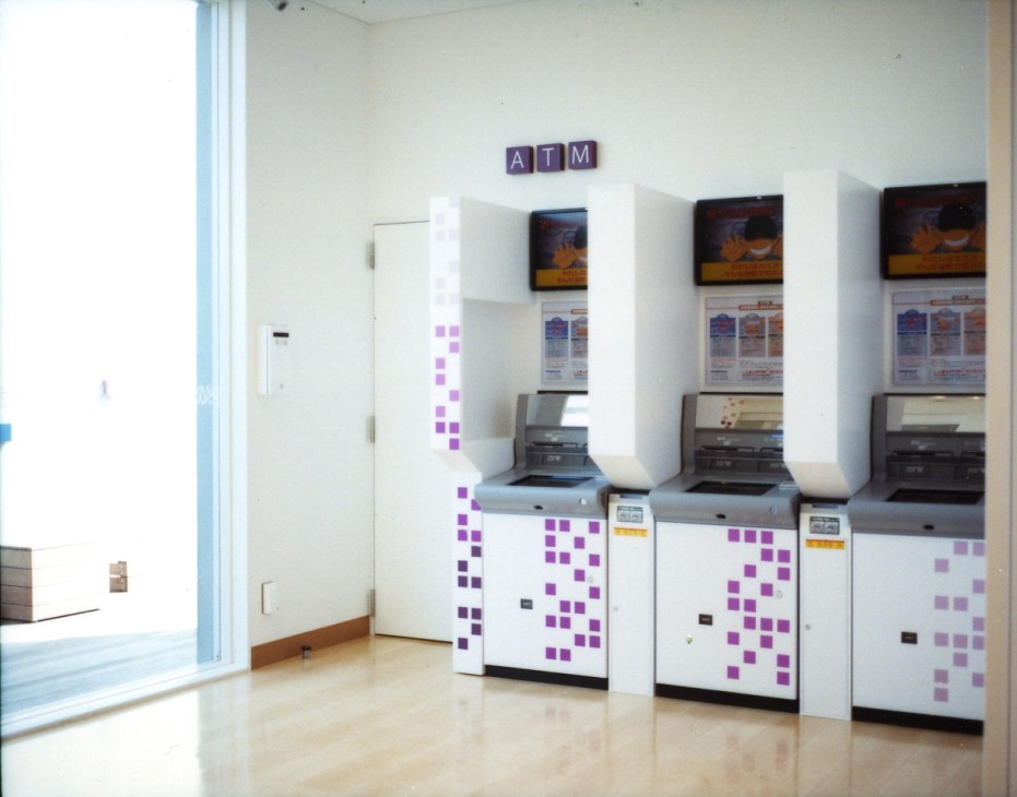 ATM machines with white enclosures decorated with purple and pink square patterns at Sugamo Shinkin Bank's Niiza branch.