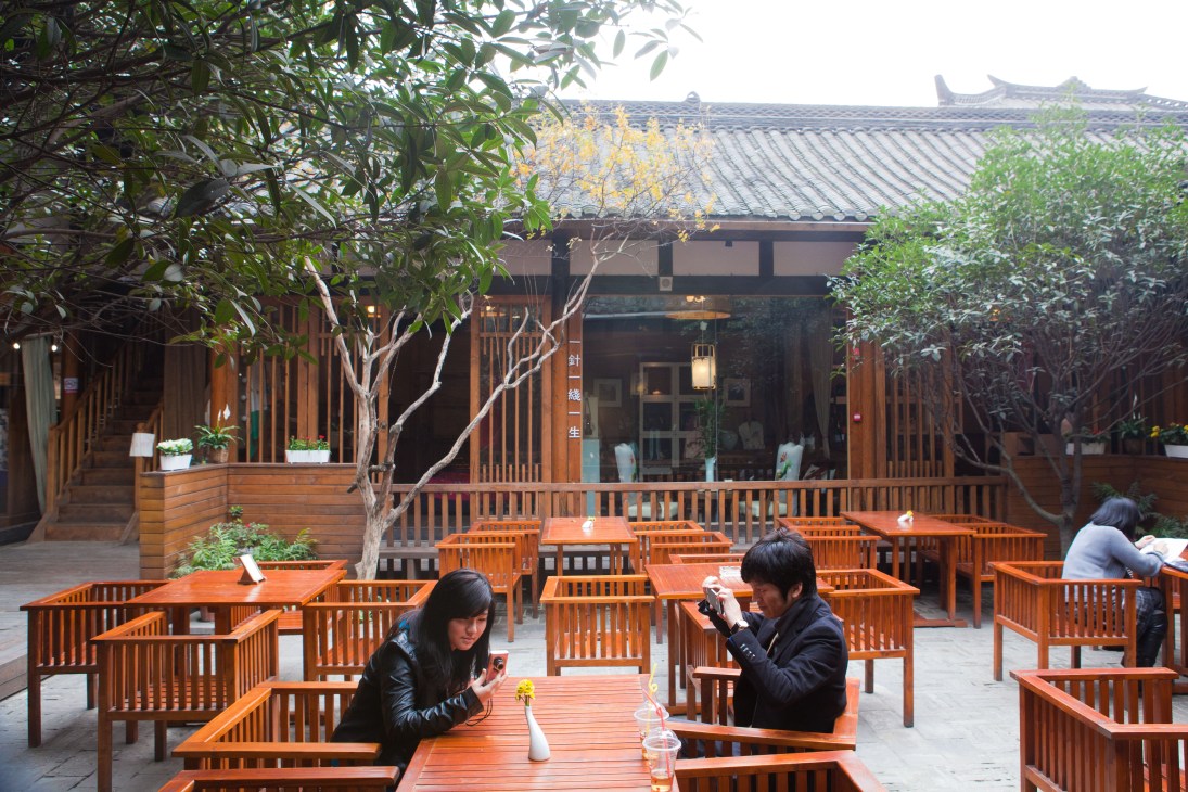 Tea house courtyard in Kuanzhai Alleys with wooden furniture and traditional Chinese architecture.