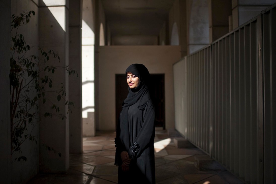 Safiya Al Humaidy, strategic planner for Abu Dhabi Authority for Culture & Heritage, stands in a modern corridor wearing black traditional dress.