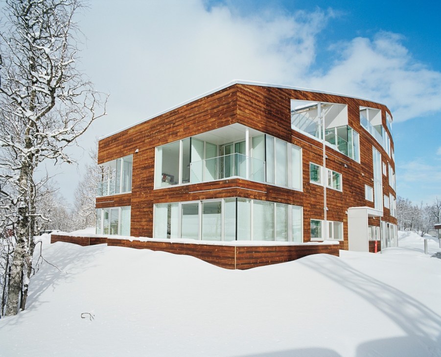 Modern wooden house with large windows in snowy landscape near Tromsø, Norway.