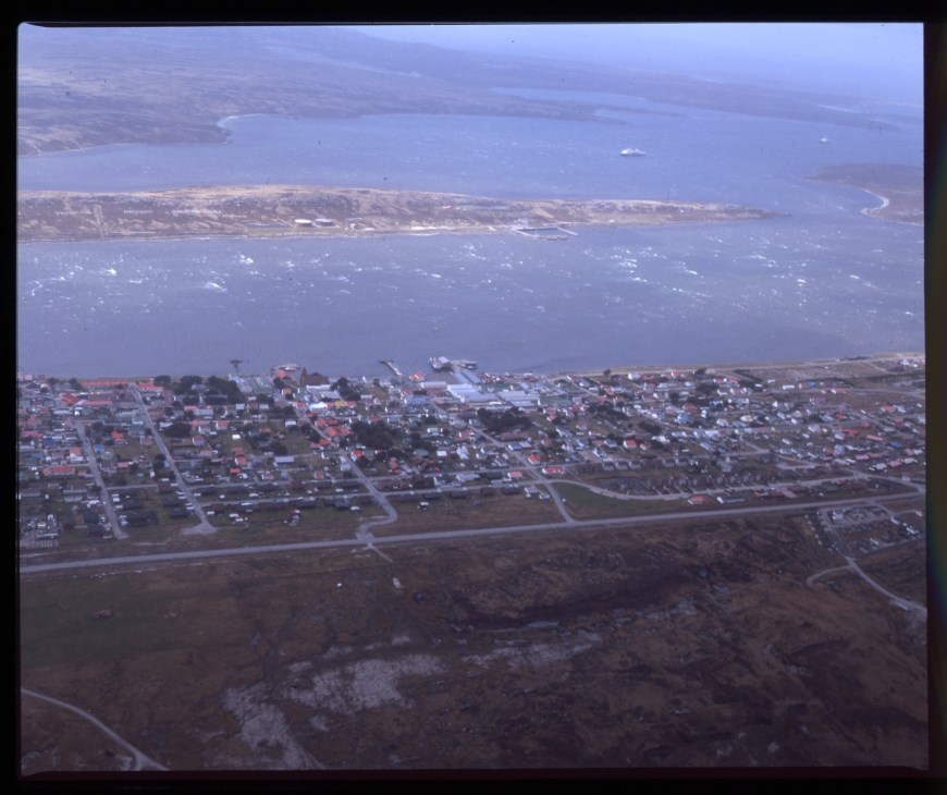Aerial view of Stanley, Falkland Islands, showing colorful buildings and harbor from a small aircraft.