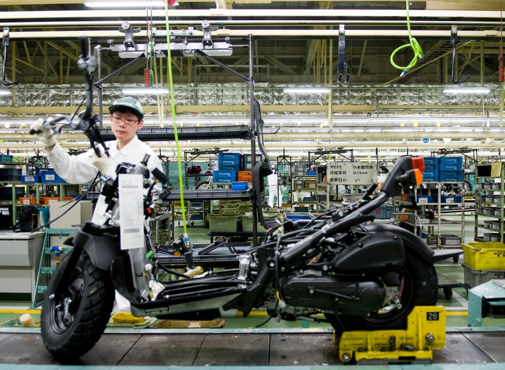 Worker fitting handlebars to a Honda scooter on the assembly line at the Kumamoto factory.