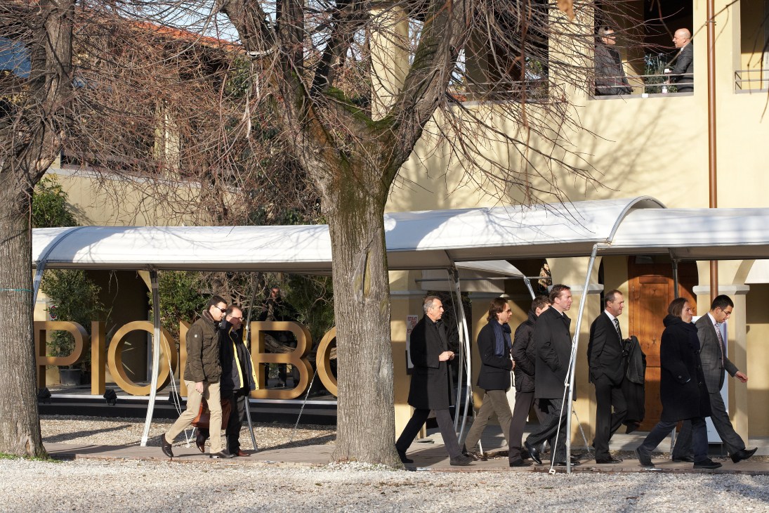 Visitors walking into the Pitti Immagine Uomo exhibition hall entrance under white awnings.