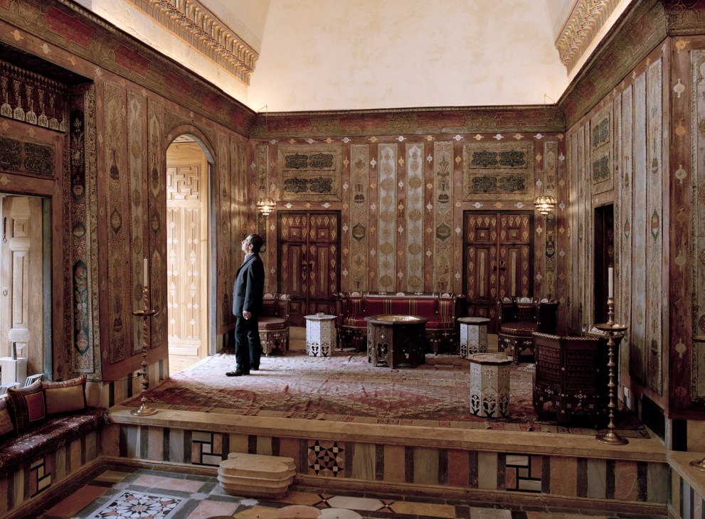 Rolan Chelhot stands in an ornately decorated room with inlaid wooden walls and traditional Islamic design elements at the Al Mansouriya hotel.
