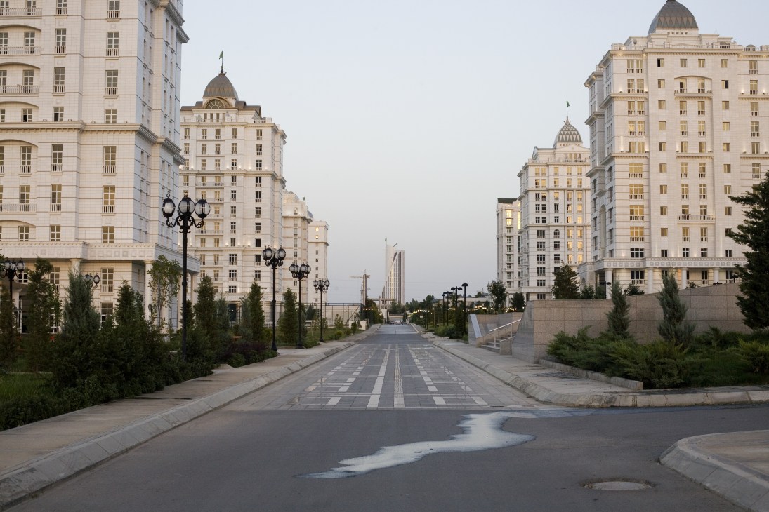 A wide street lined with marble-clad apartment buildings with golden domes in Ashgabat, Turkmenistan.