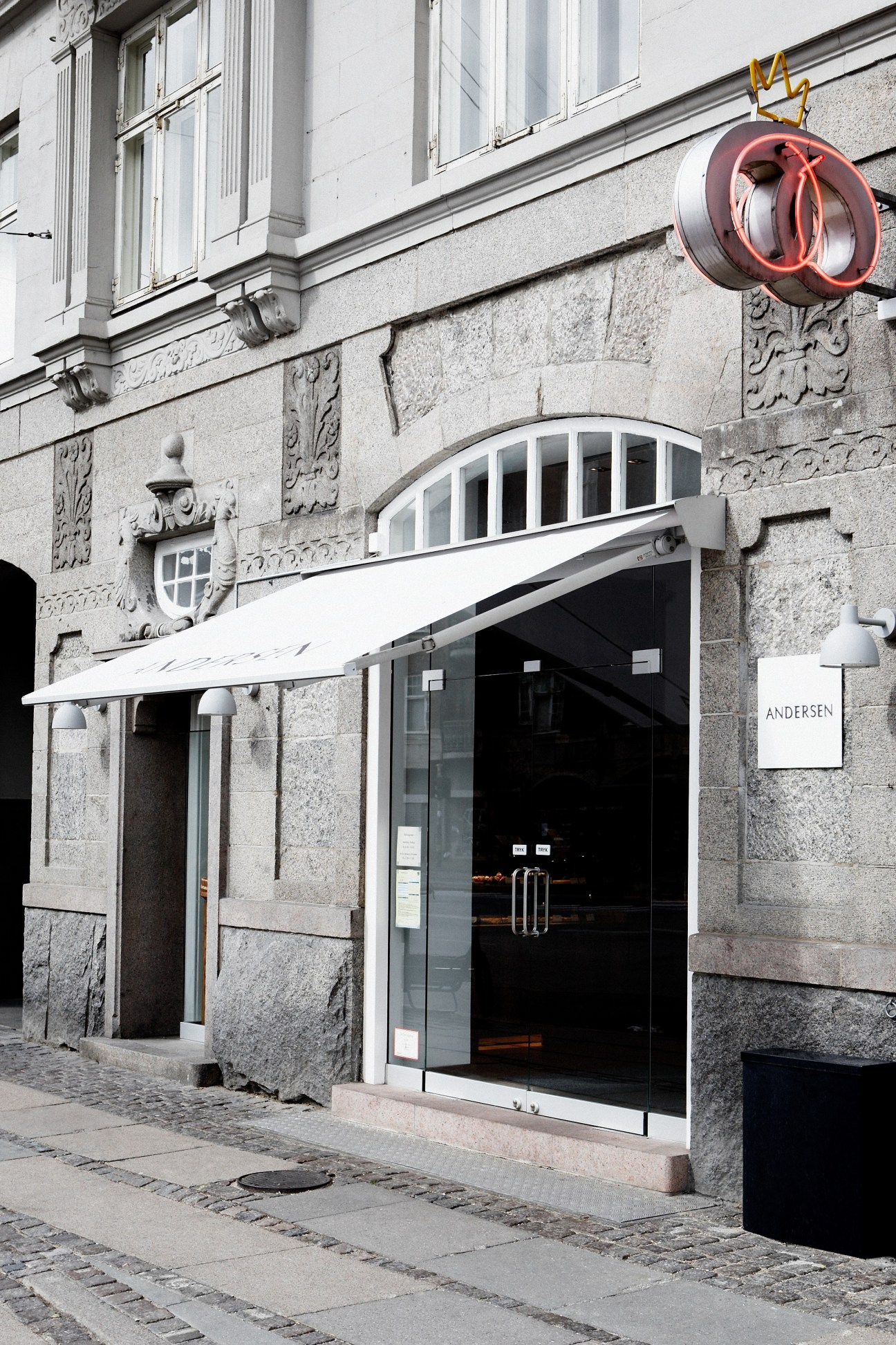 Andersen bakery storefront in Copenhagen with red neon pretzel sign above the entrance.