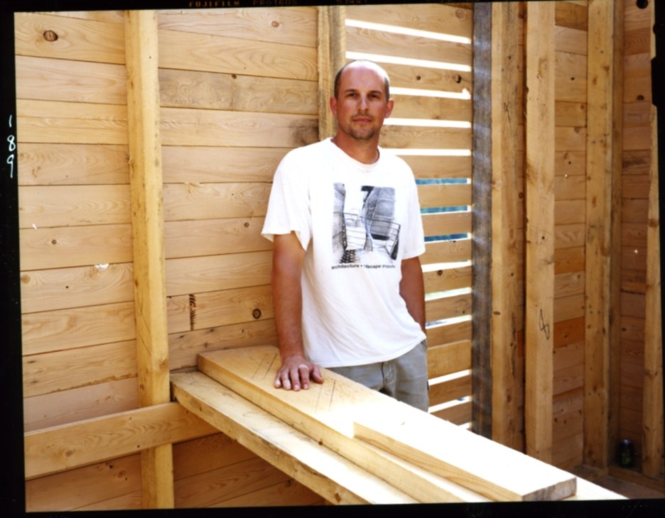 Arkansas architect Jonathan Boelkins standing inside wooden building frame construction.