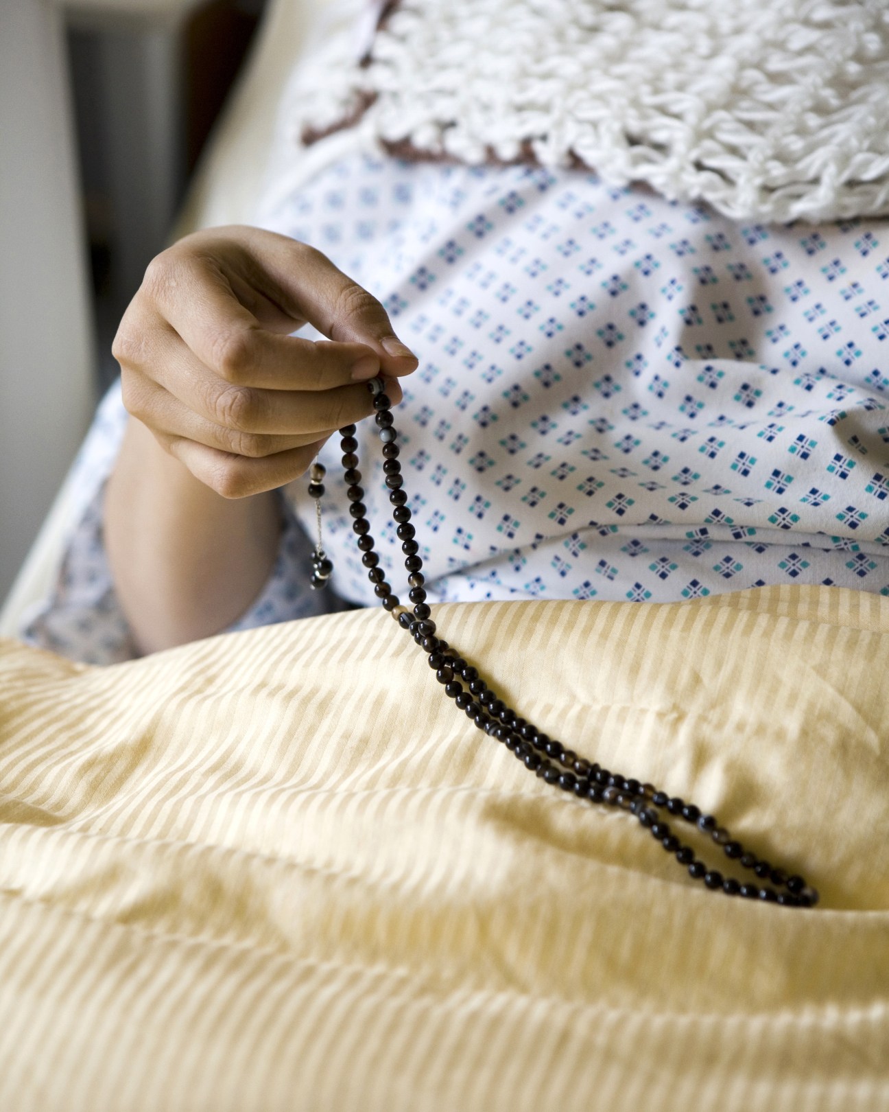 Saudi patient Alnaimi Afaf holds prayer beads while lying in a hospital bed at UKE medical centre in Hamburg.