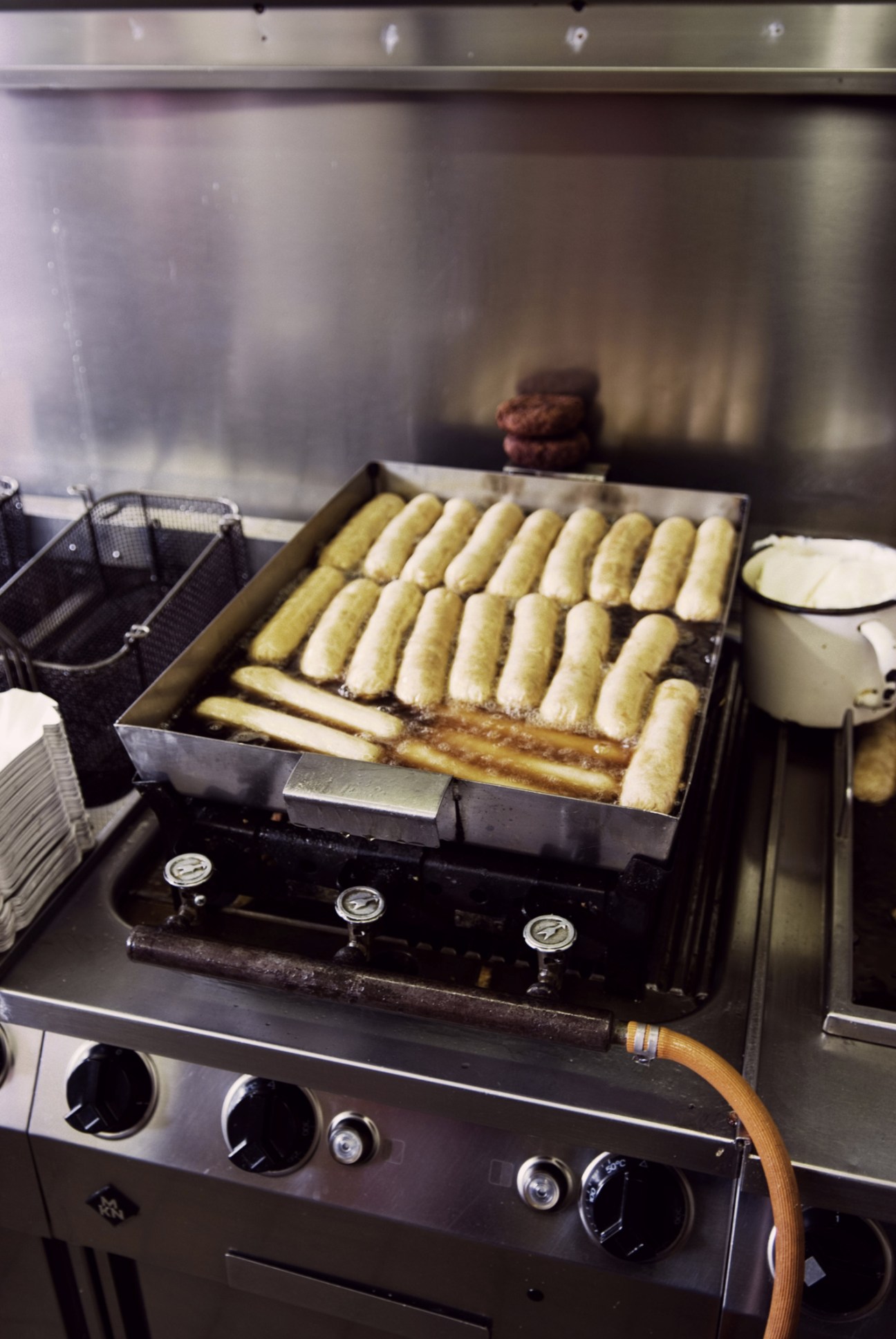 Sausages cooking in a metal tray on a commercial griddle at Konnopke's.