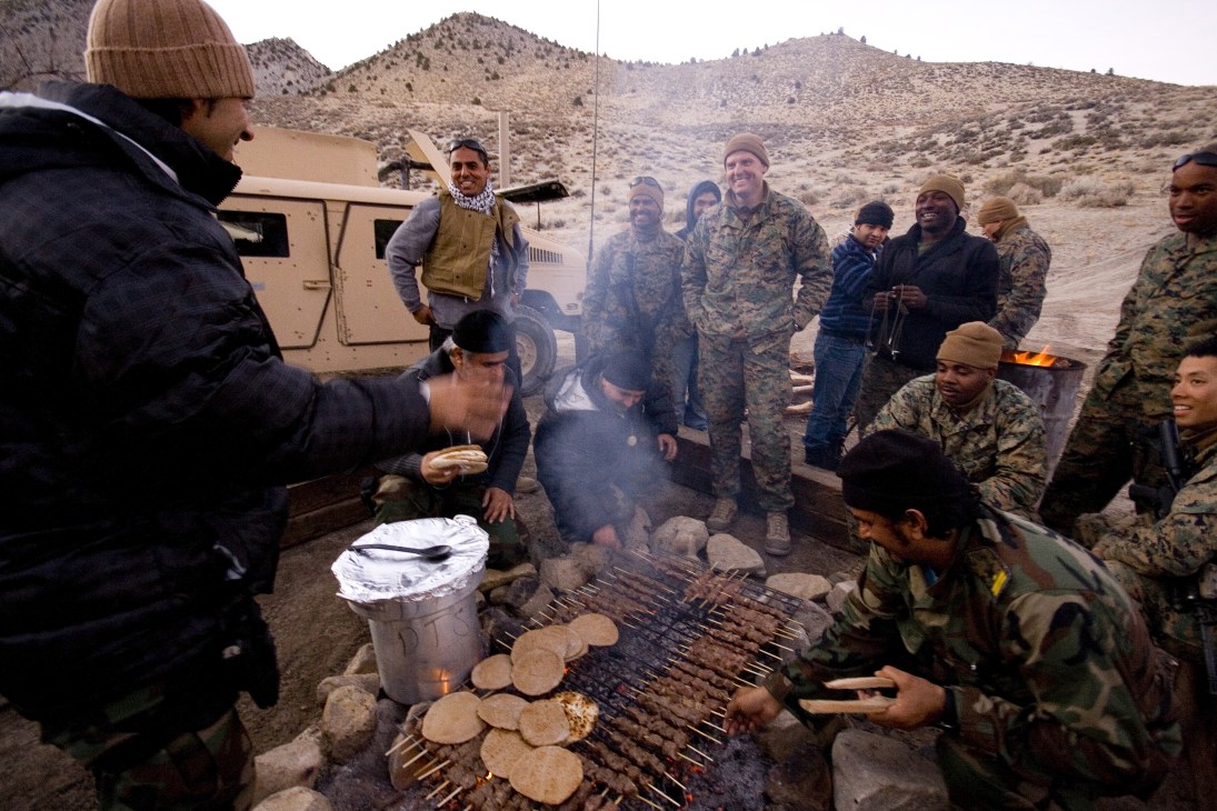 Marines and Afghan role players take a break around a fire grilling kebabs in the Nevada desert during Mountain Viper training.