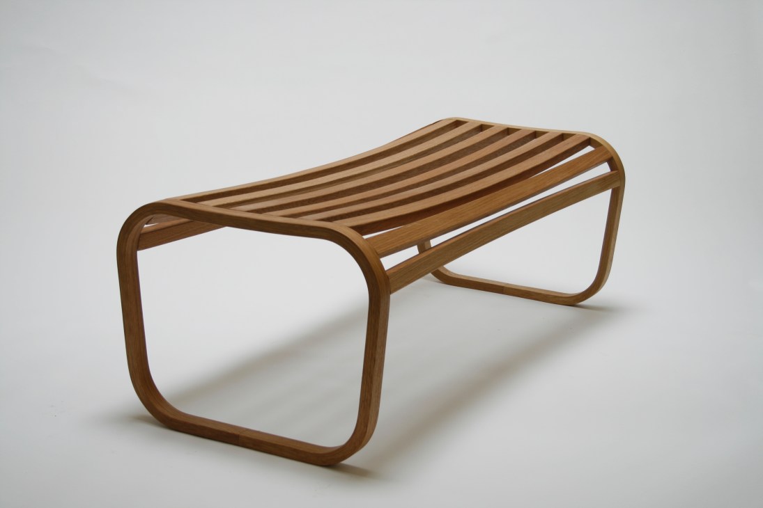Wooden bench with curved legs and slatted seat made from white oak.