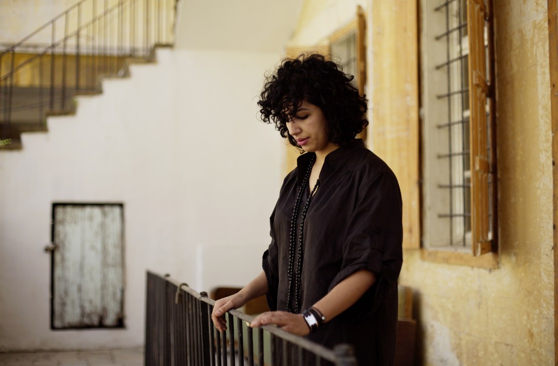 Dalila Barkache, co-owner of Beirut's Comme des Garçons Guerrilla store, standing on a staircase in a traditional Ashrafieh building.