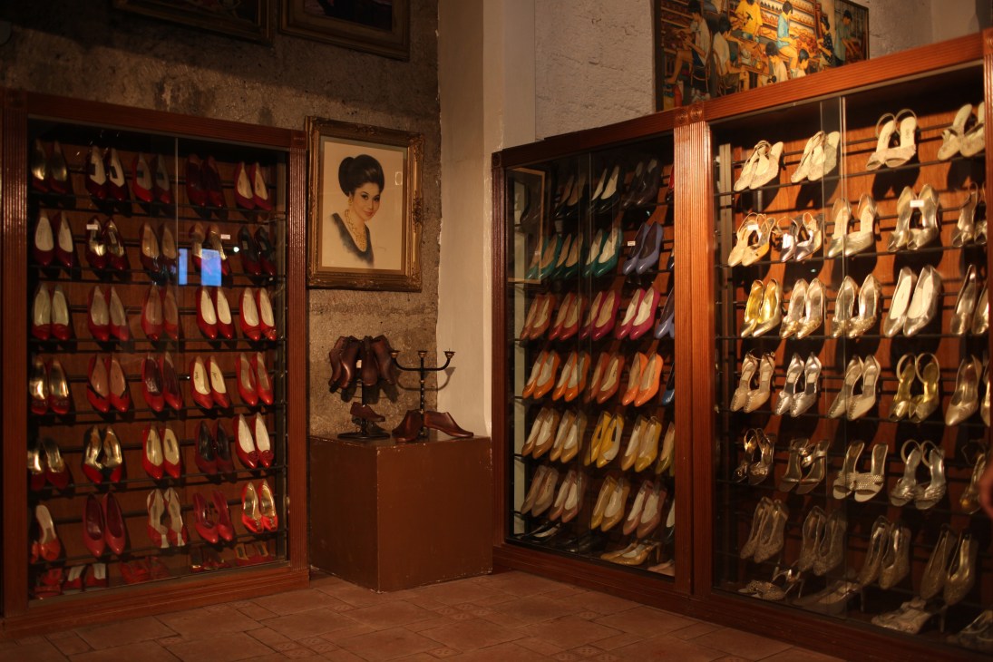 Display cases filled with hundreds of colorful shoes in the Marikina Shoe Museum, with a framed portrait of Imelda Marcos on the wall.
