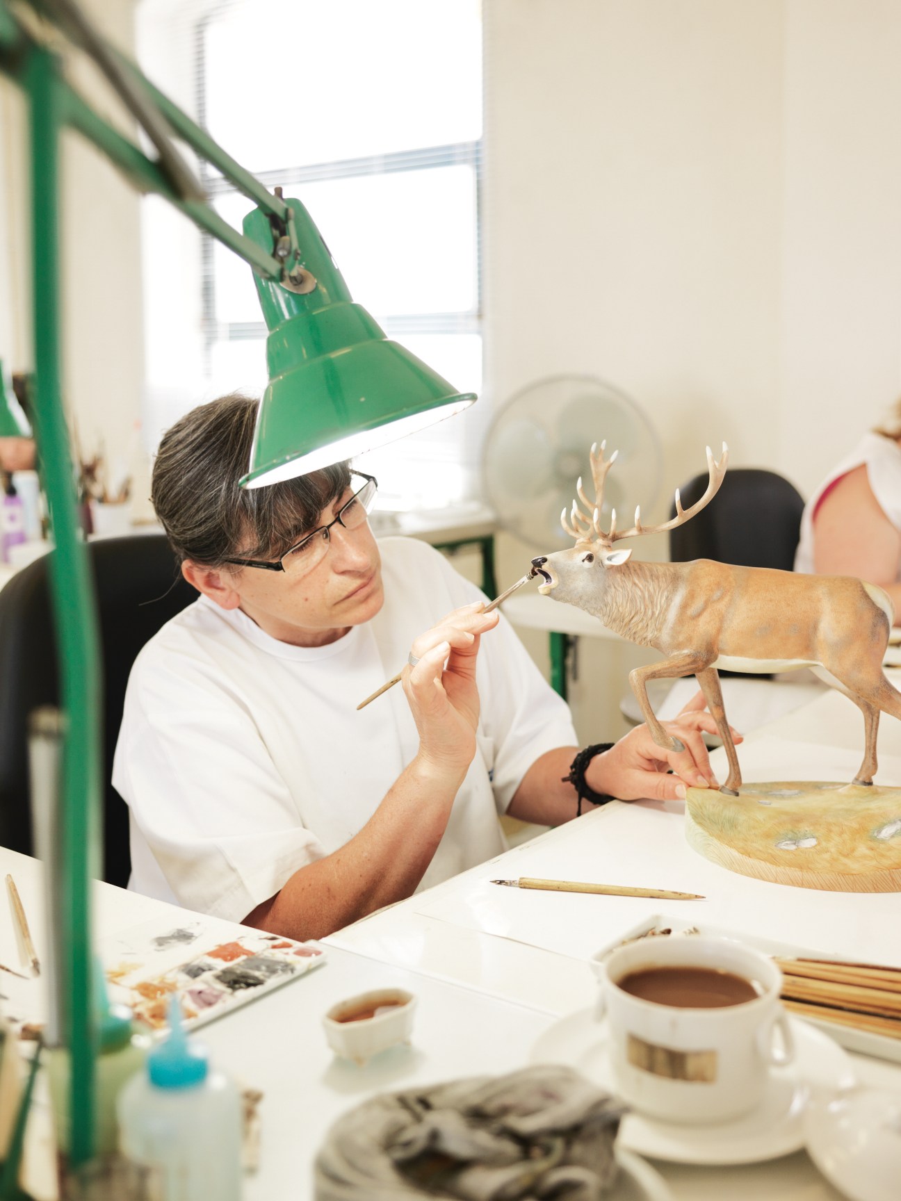 Artist hand-painting fine details on a porcelain deer figurine in the Vista Alegre studio.