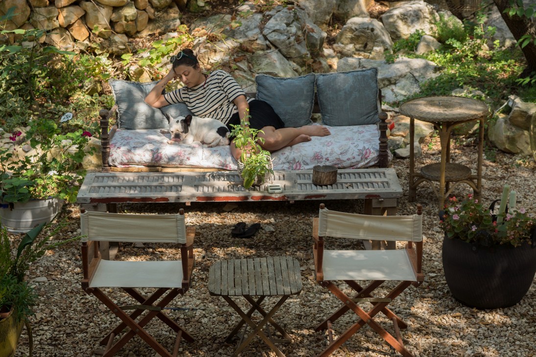 Rasha Kahil relaxes on a cushioned daybed with the resident French bulldog Kloe in Beit al Batroun's lush garden terrace.