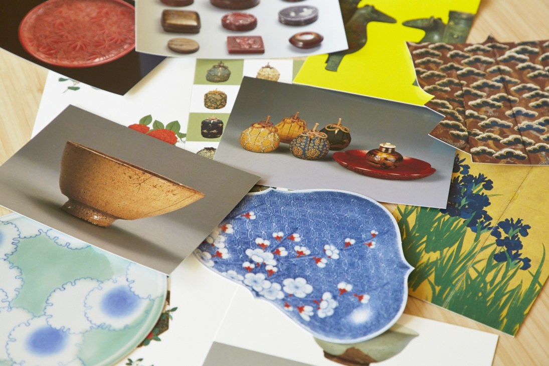 Display of Japanese ceramic tea ceremony pieces and museum postcards arranged on a white surface.