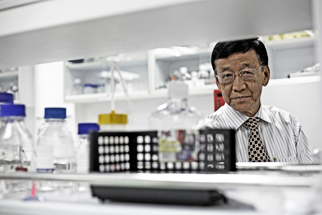 Dr Gan Ee Kiang, a pharmacologist, stands in a laboratory with scientific equipment and bottles behind him.