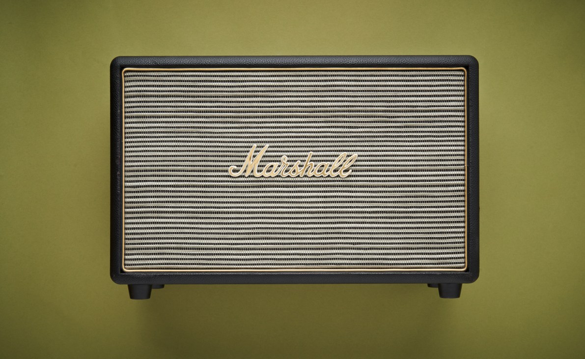 Marshall Hanwell home speaker with black vinyl cladding and brass controls against a green background.