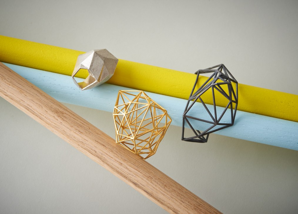 Geometric jewelry pieces in brass, bronze and silver from Lotocoho's Ergonomic Territories collection arranged on colored surfaces.